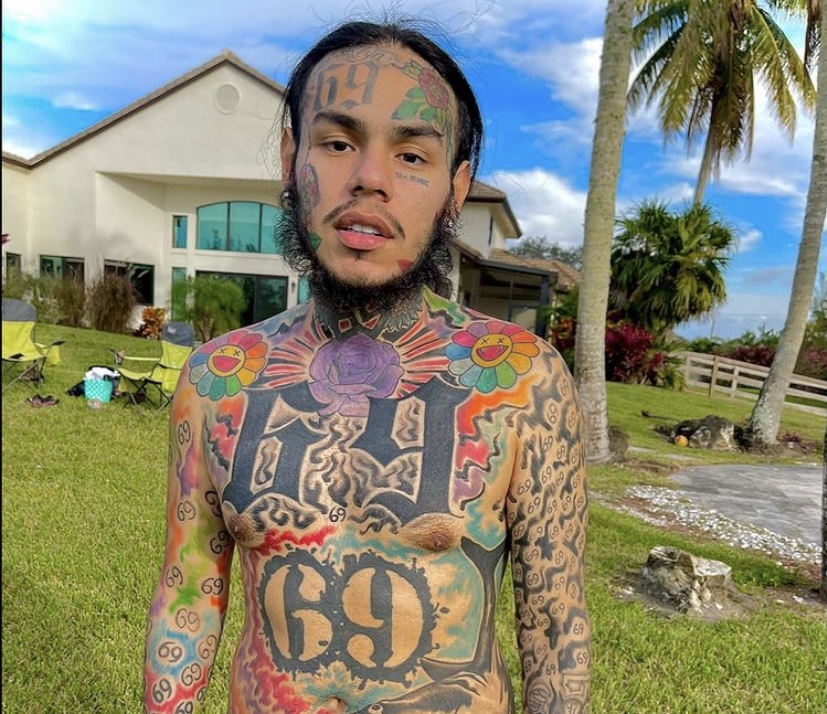 6ix9ine showing off his new tattoos.