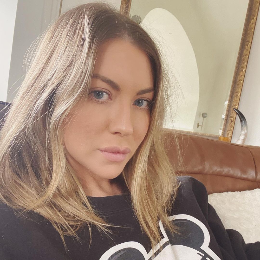 A photo of Stassi Schroeder without make-up, sitting in the comfort of her home, in a black sweatshirt.