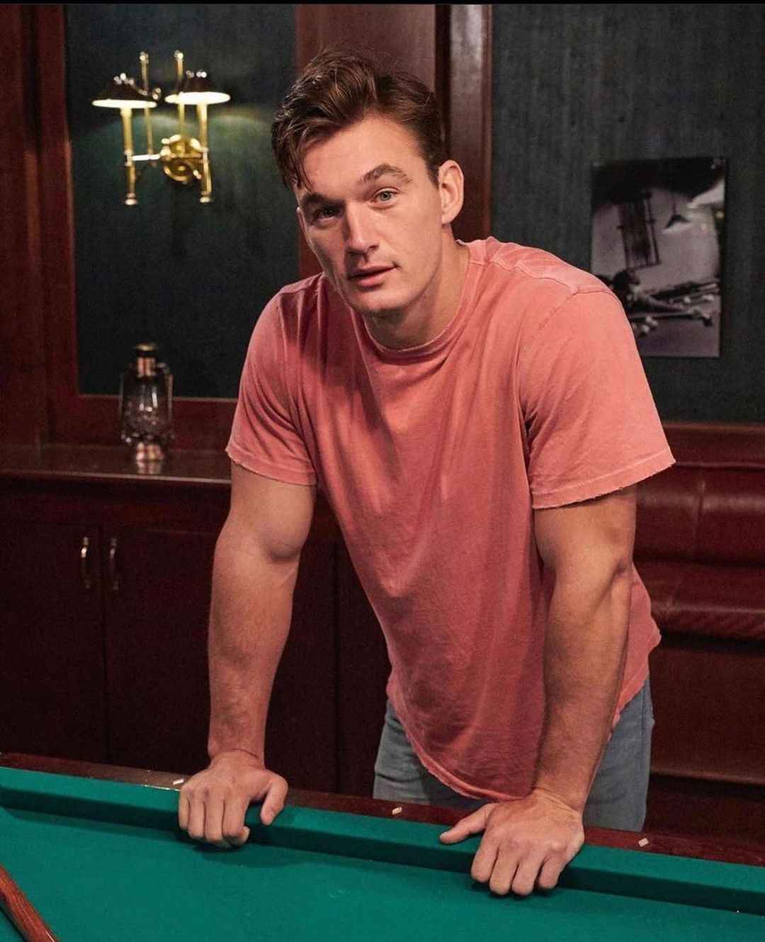 A photo of Tyler Cameron in a casual outfit, leaning on a pool table.