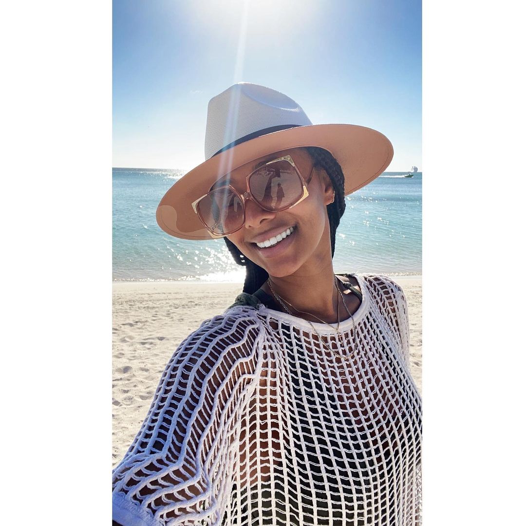 A photo showing Keri Hilson in a white net outfit, socaking up the sun at the beach.