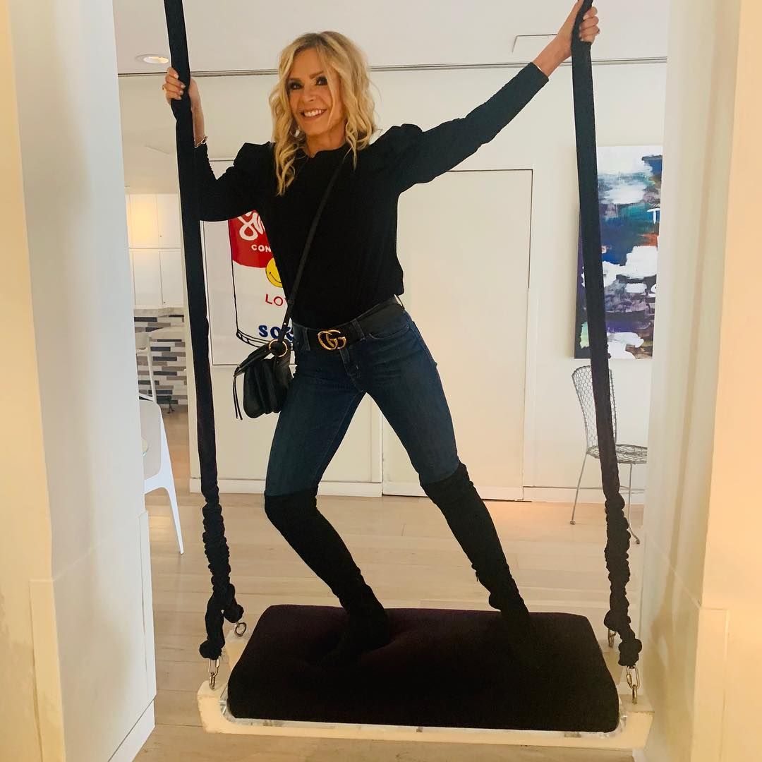 Tamra Judge stands on a swing.