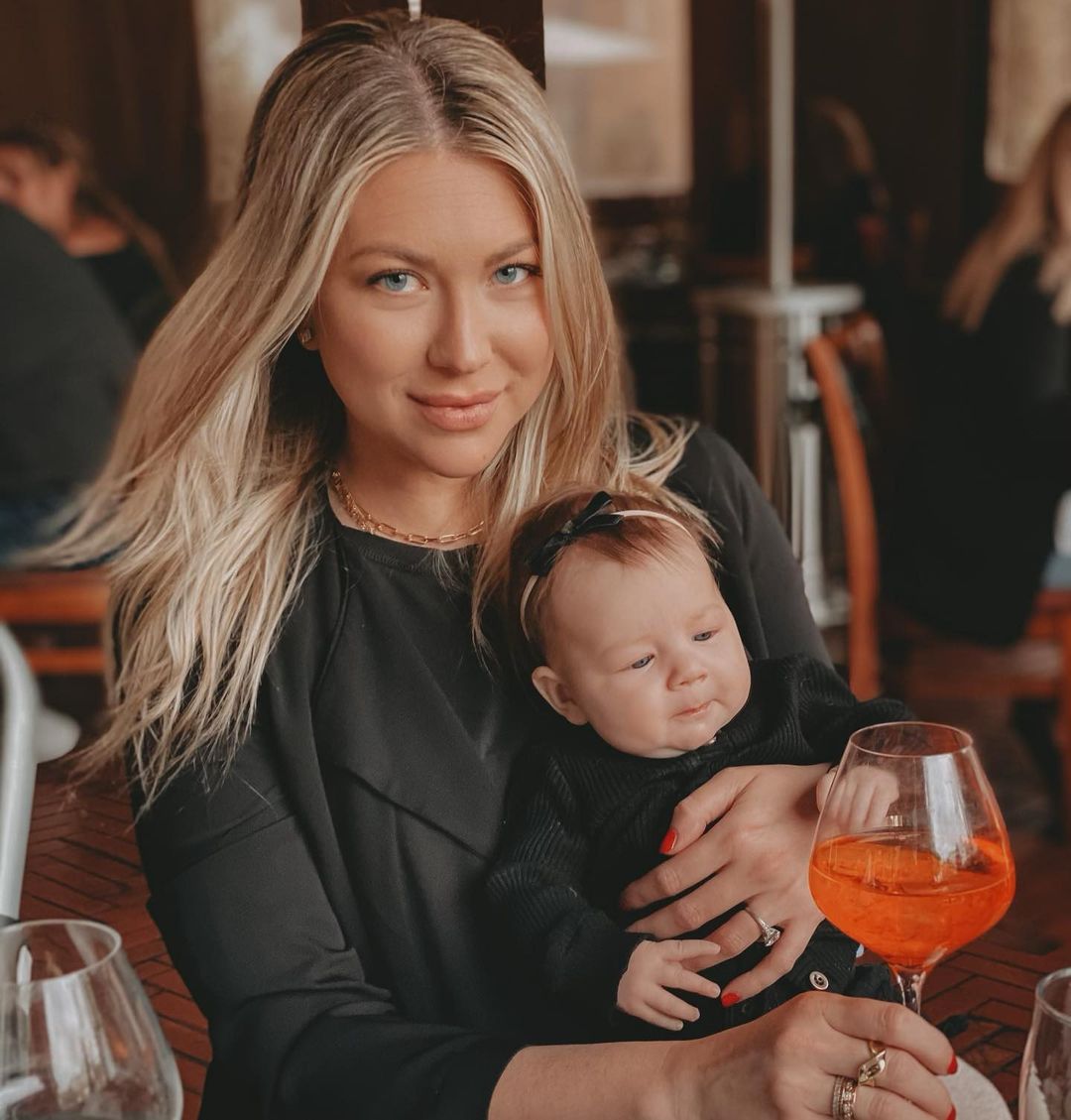 A photo showing Stassi Schroeder holding her baby during a date, with a glass of wine in front of her.