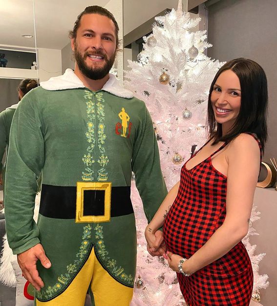 Brock Davies wears an elf costume as Scheana Shay sports a red and black checkered dress.