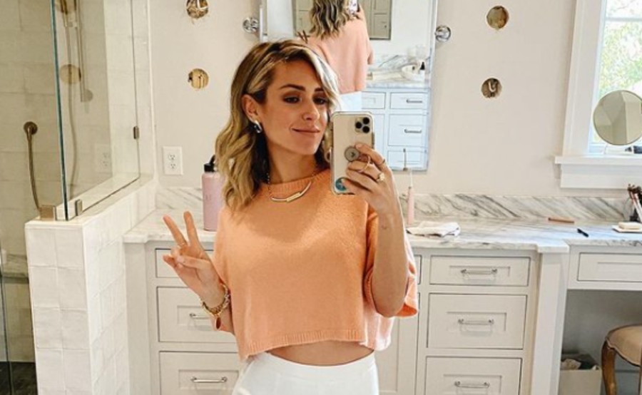 Kristin Cavallari gives a peace sign in a peach crop top.