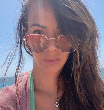 Kristen Doute takes a selfie with sunglasses at the beach.