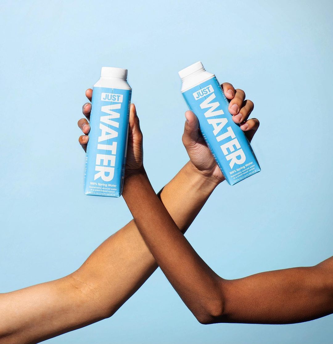 A picture of two hands holding a bottle with reads 'Just Water.'