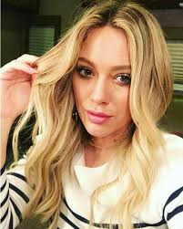 Hilary Duff taking a selfie in a white shirt with black stripes