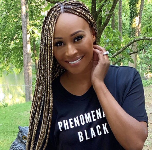 Cynthia Bailey wears braids and a 'Phenomenal Black' T-shirt.