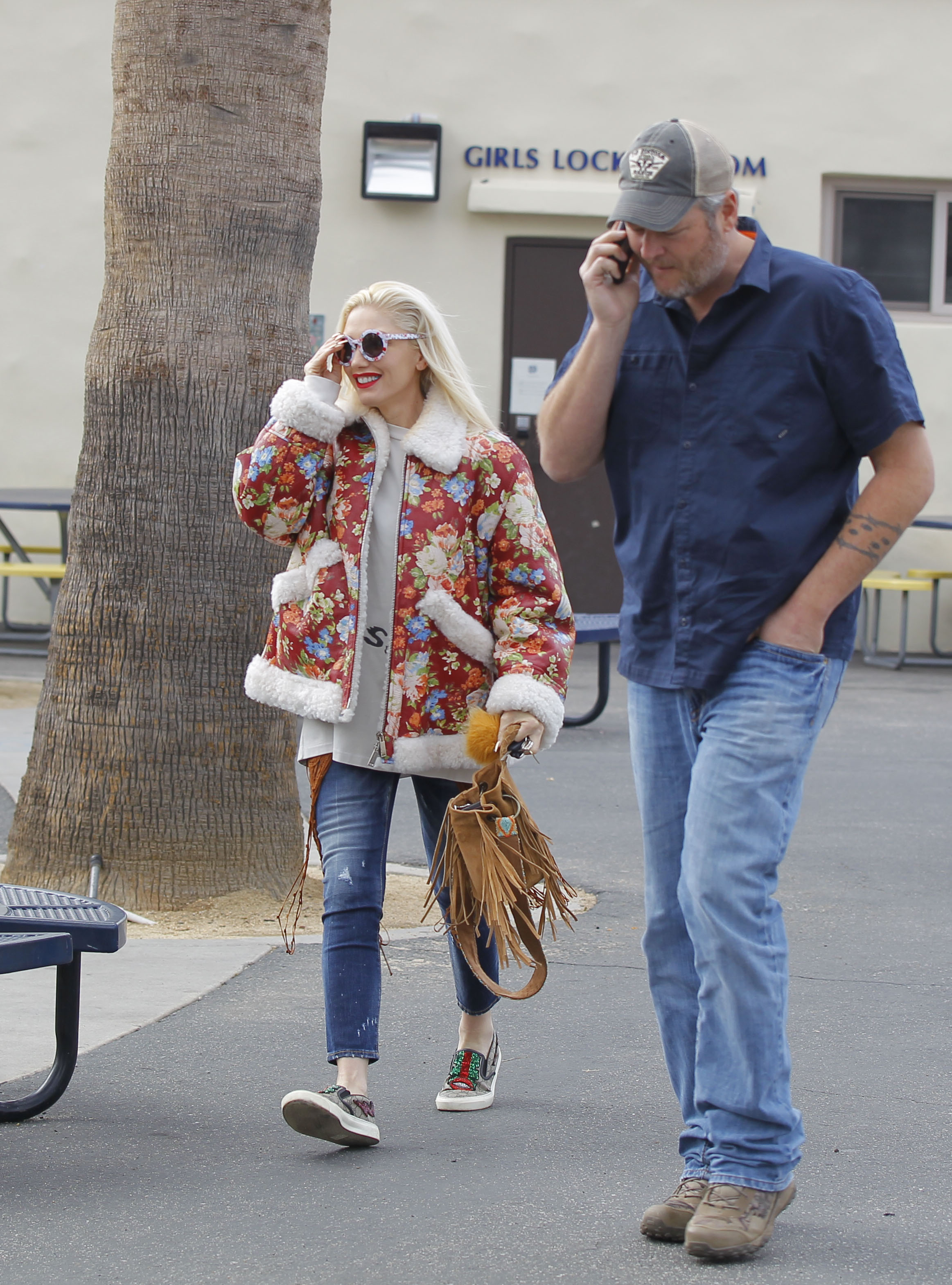 A picture of Gwen Stefani and Blake shelton taking a walk on the streets in casual outfits.