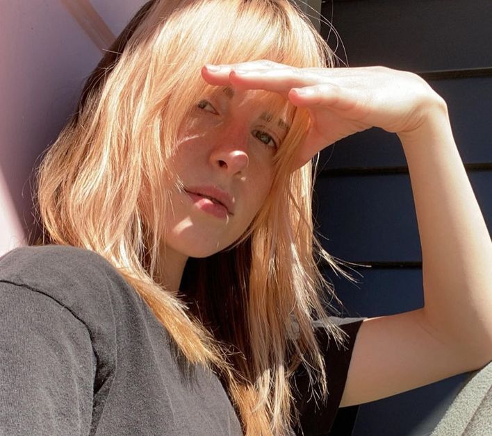 Hayley Williams holds up her hands to block the sun out of her eyes as she takes a selfie.