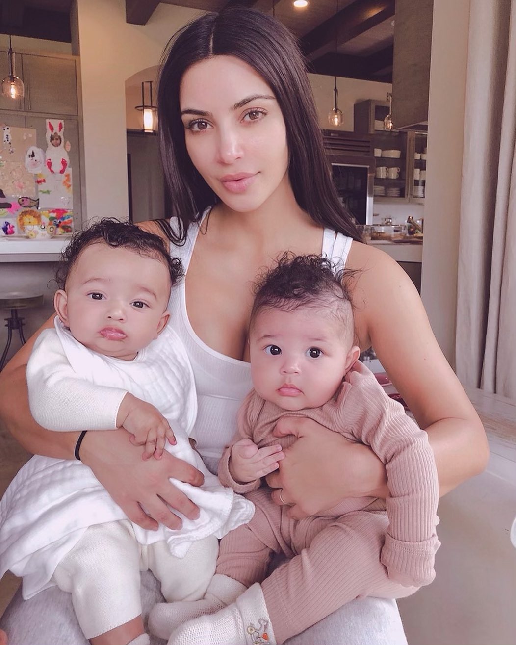 A photo showing Kim Kardashian holding her baby and her niece in both arms and they look very adorable.