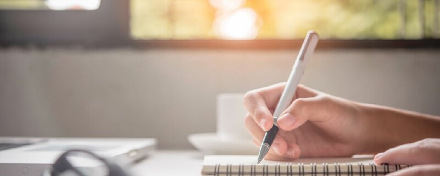person writing notes on desk