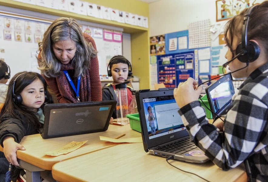 Teacher working with student while AI interface is visible on screen