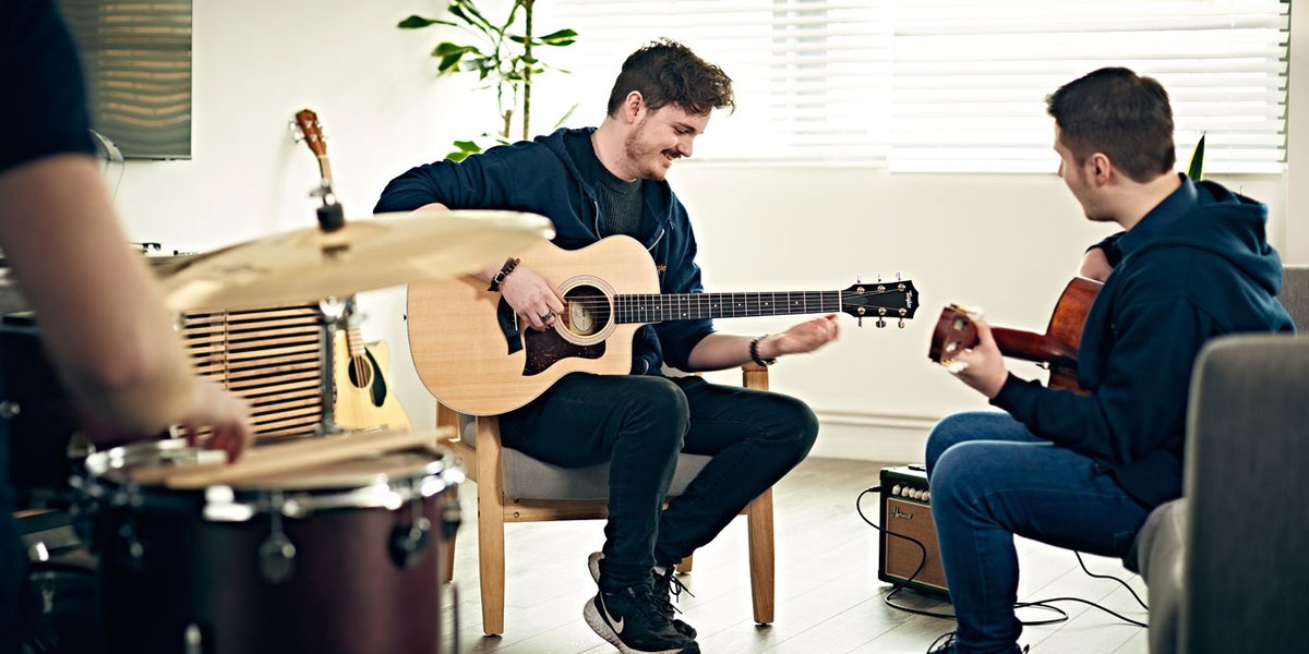 Two individuals practicing together on acoustic guitars.