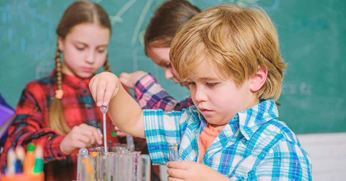 Young children engaged in a hands-on STEM activity with colorful tubes and balls