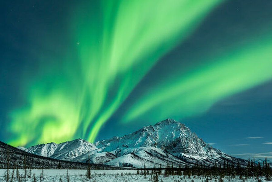 Northern Lights display over a landscape in Alaska.