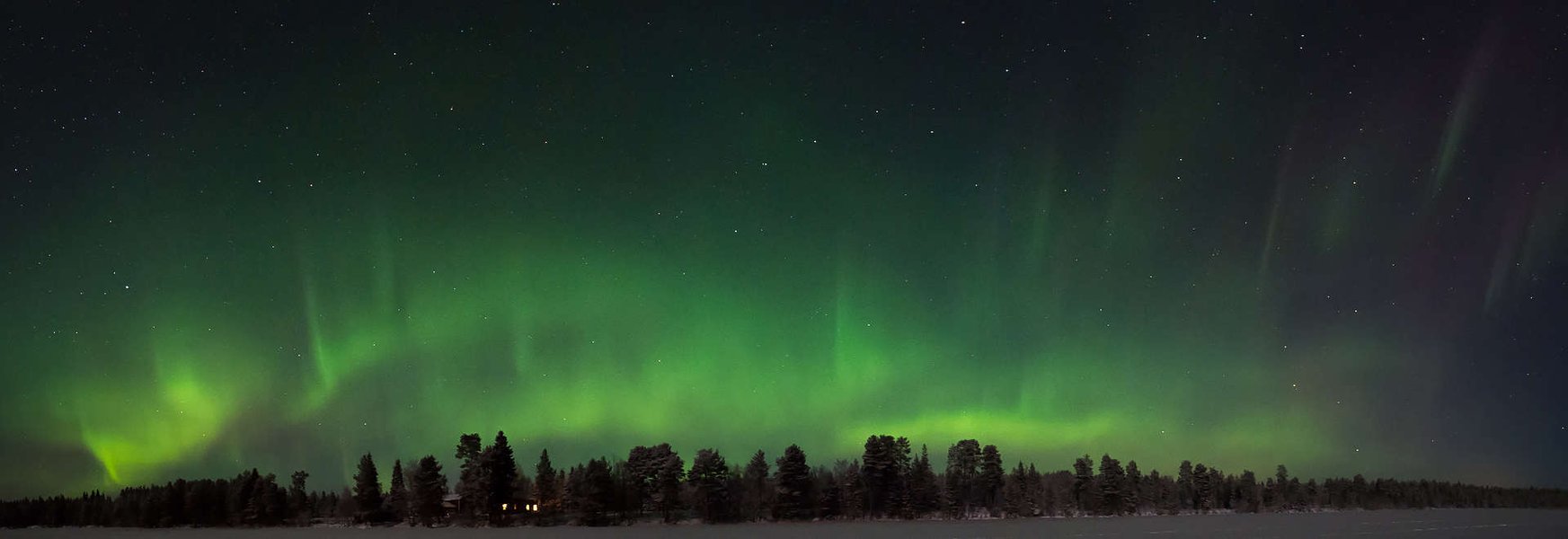 Northern Lights over a snowy landscape in Finland.