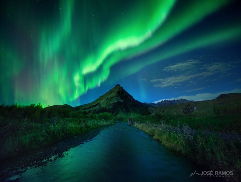 Intense green and purple aurora over a dramatic Icelandic landscape
