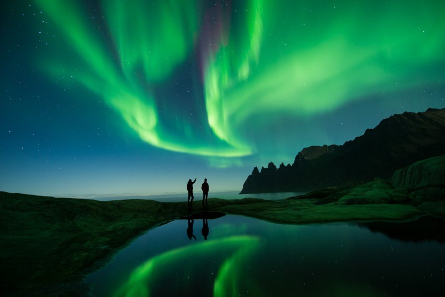 Group of people warmly dressed, looking up at the Northern Lights