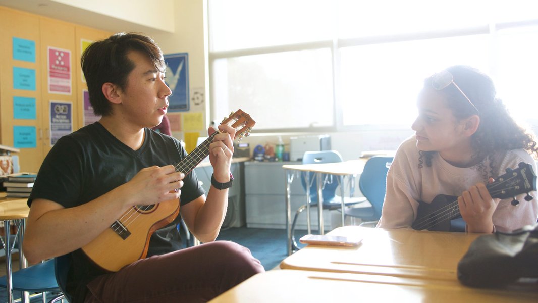 Music teacher guiding a student playing the violin