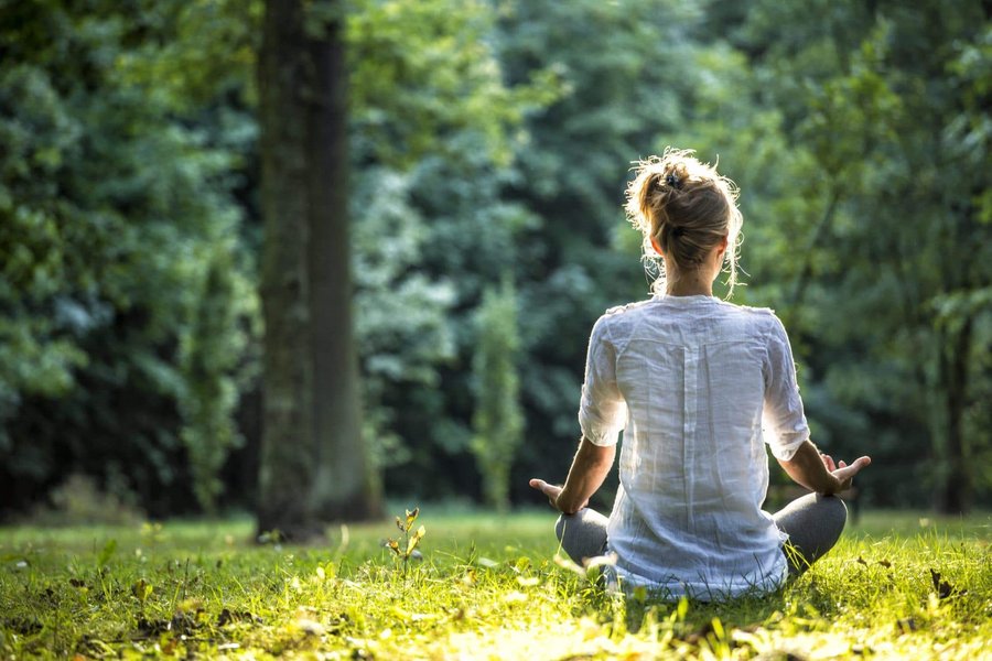 Person sitting in a comfortable meditation posture indoors