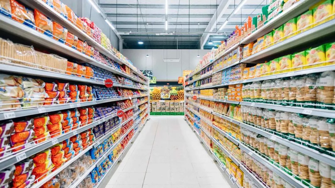 Interior de un pasillo de supermercado con estanterías llenas de productos