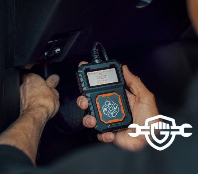 A person plugging an OBD-II scanner into a car's diagnostic port.