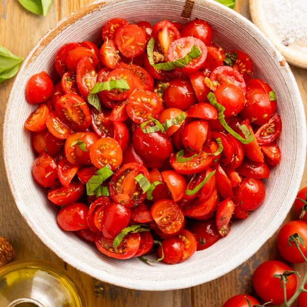 A vibrant cherry tomato salad with fresh herbs and cheese, perfect for a light and healthy meal.