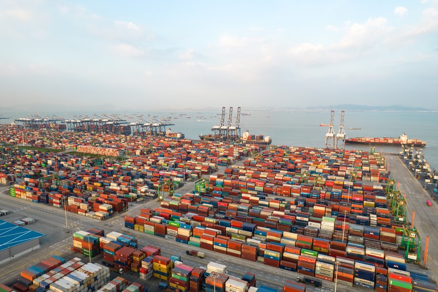Aerial view of a busy container port with cranes and ships.