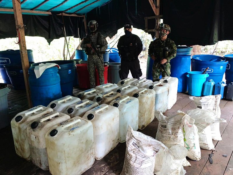 Destroyed clandestine cocaine laboratory showing barrels and processing equipment.