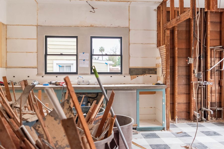 Demolition work in progress in a kitchen area, showing debris and tools.