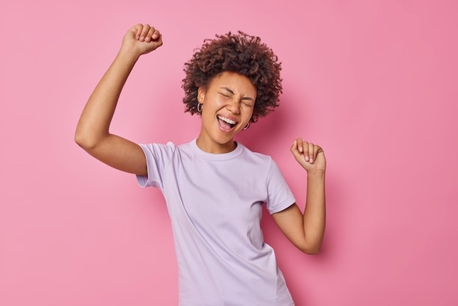 Mujer con cabello rizado bailando felizmente, celebrando su libertad y alegría