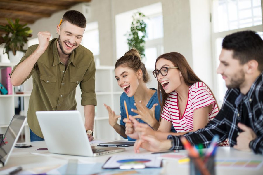 Group of people working together on laptops, looking joyful