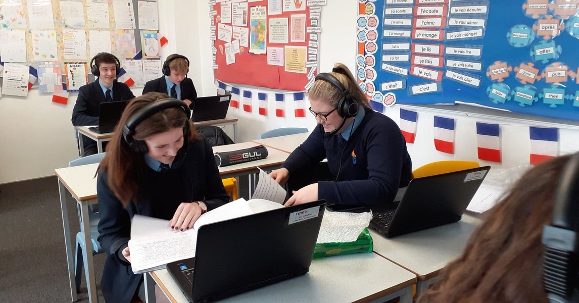 Language classroom setup with students using headphones and computers