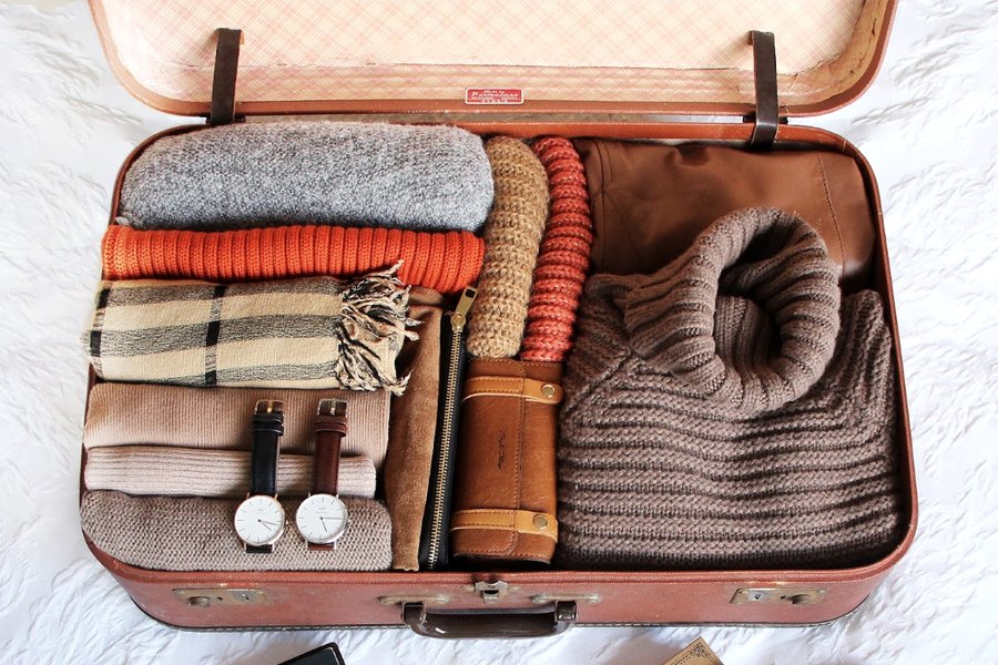 Clothes neatly rolled and arranged inside a suitcase
