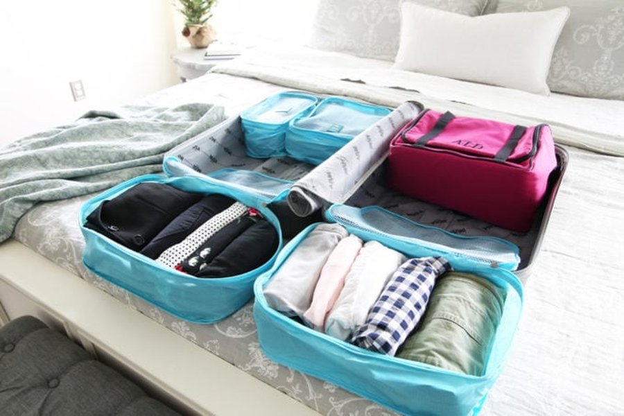 Various sizes of packing cubes, some open and filled with clothes, others zipped and compact.
