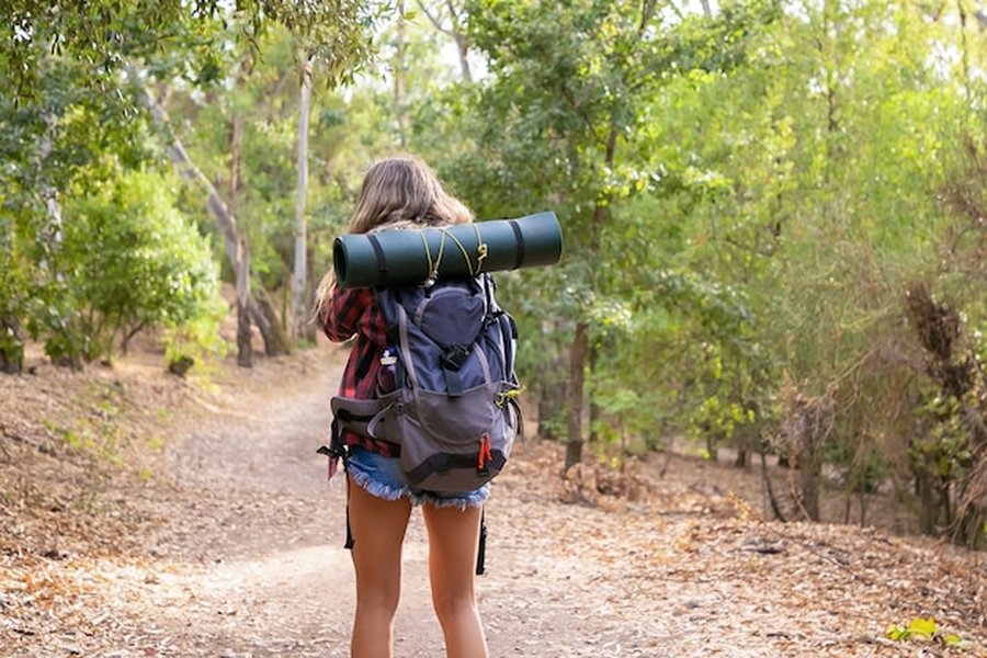 Mujer caminando con mochila por un sendero forestal