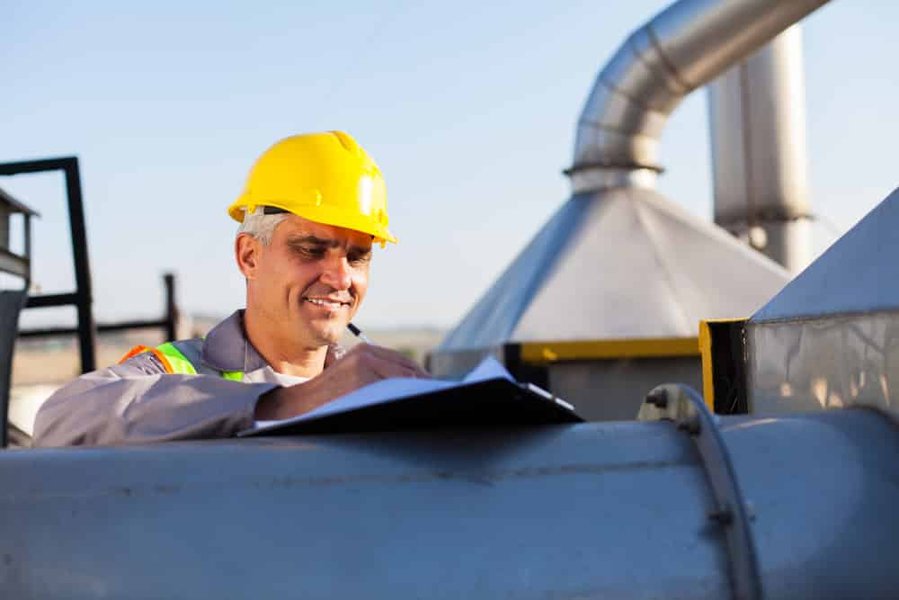 Auditor in safety gear conducting an on-site inspection with a clipboard