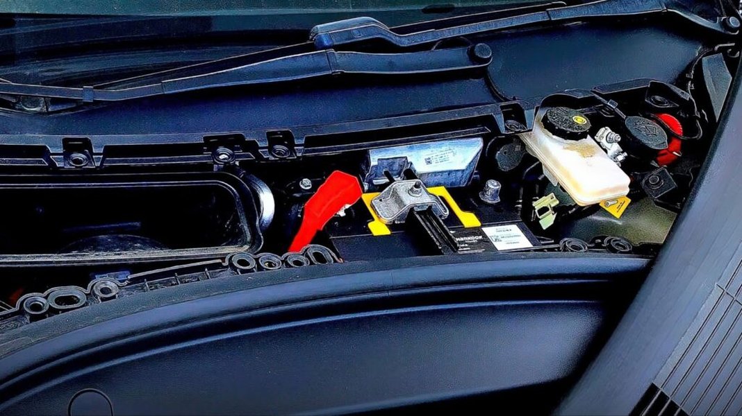 A technician replacing a 12V battery in a Tesla frunk.