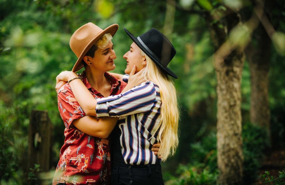 Two women in wedding attire smiling and looking at each other affectionately