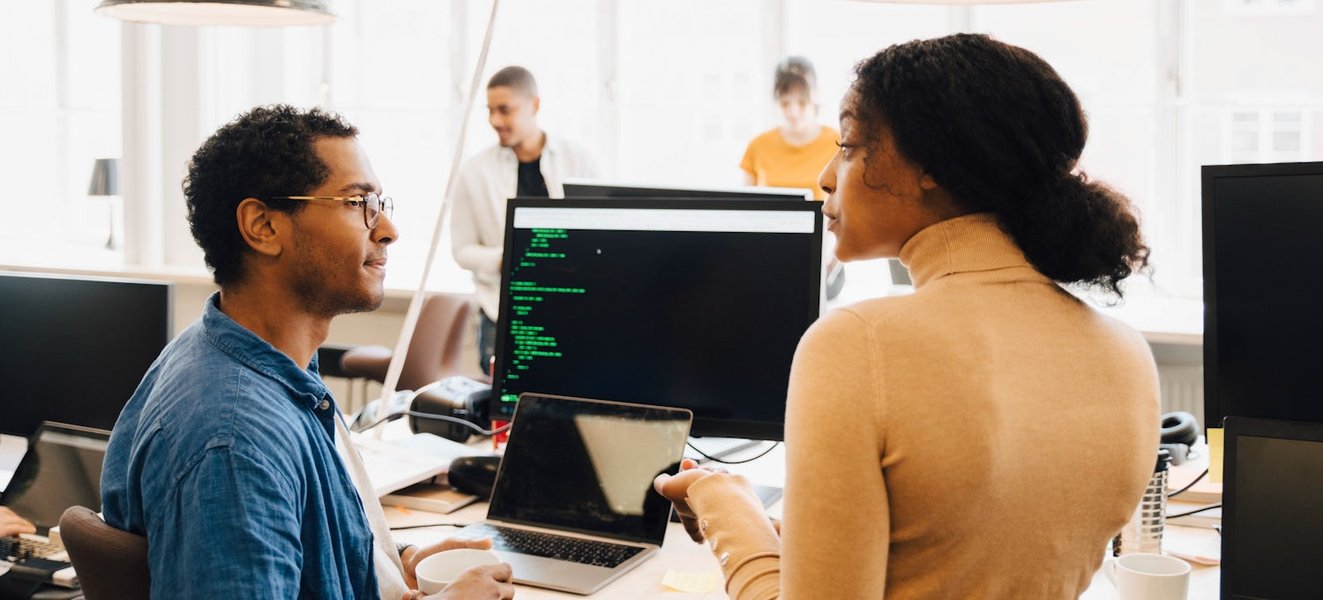 Students working on computers in a coding bootcamp setting.