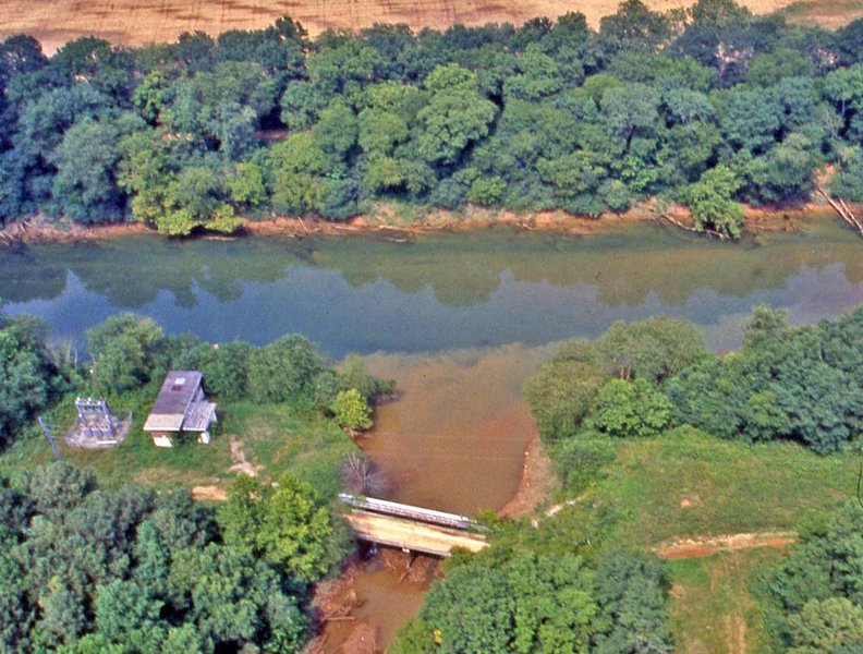 A sediment-laden tributary flowing into a clearer river, showcasing sediment transport.
