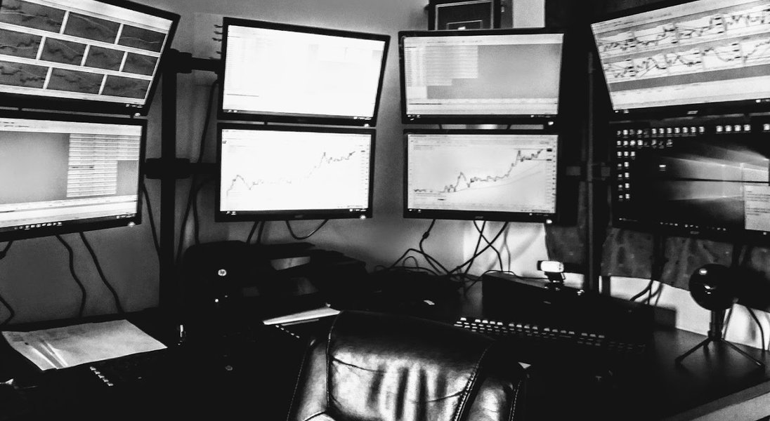 Forex trading room with multiple monitors displaying charts