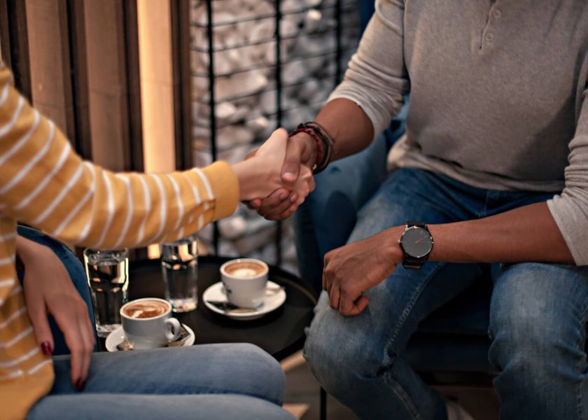 A man and woman shaking hands, symbolizing the initial greeting and the start of a connection on a first date.