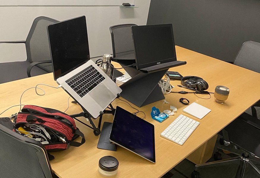 A person working on a laptop in a cafe, with a backpack nearby.