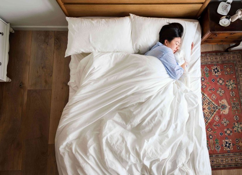 A person lying in bed, potentially experiencing difficulty sleeping.