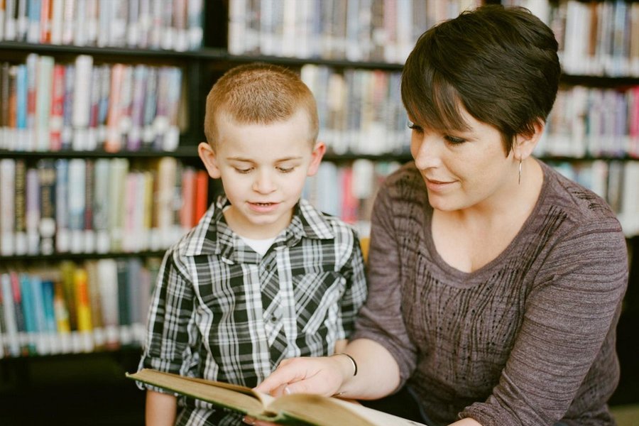 Insegnante legge un libro con un bambino, mostrando vicinanza emotiva