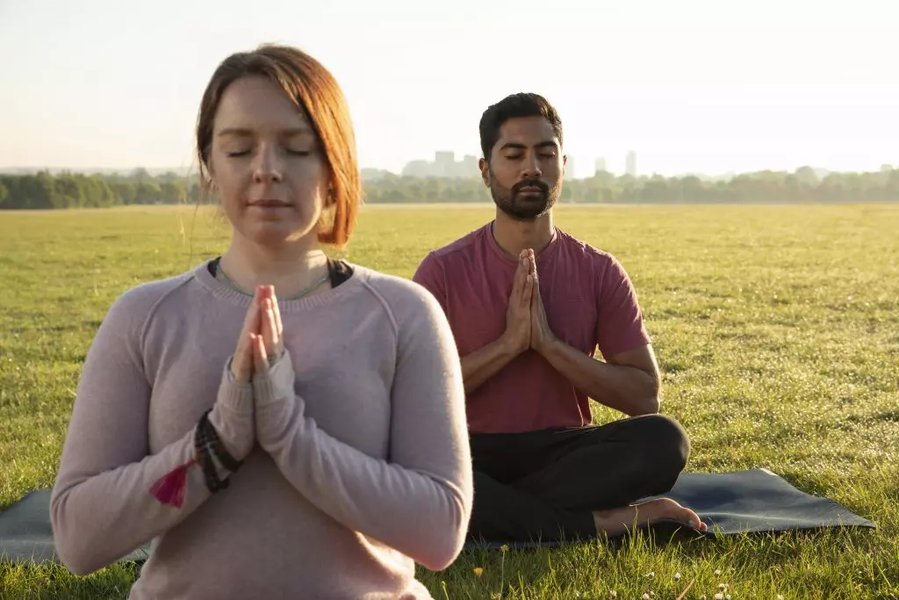 Two individuals meditating peacefully side-by-side outdoors