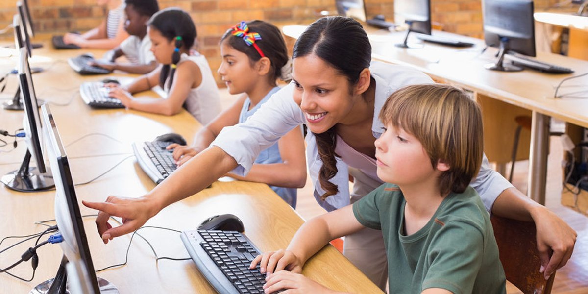 Children learning to code in a classroom setting with a teacher