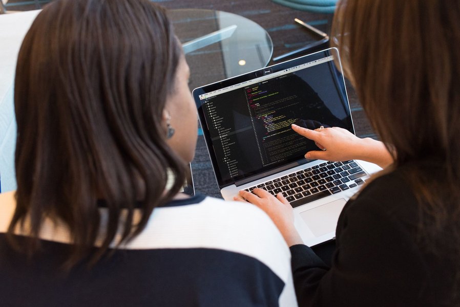 Two developers engaged in pair programming, looking at a screen with code.